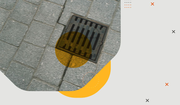 A blurred photo of a storm drain on a concrete sidewalk.